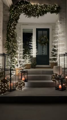 christmas decorations on the front steps of a house with candles and wreaths around them