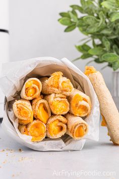 some food is in a paper bag next to a bread stick and potted plant