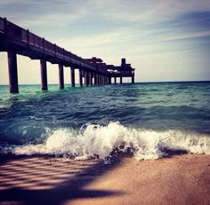 the ocean waves are coming in front of a pier