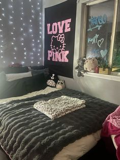 a bedroom with pink and black decor on the walls, bedding and pillows in front of a window