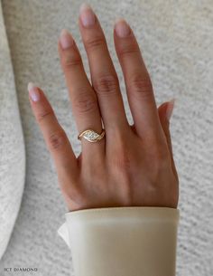 a woman's hand wearing a gold ring with a diamond on it and a white background