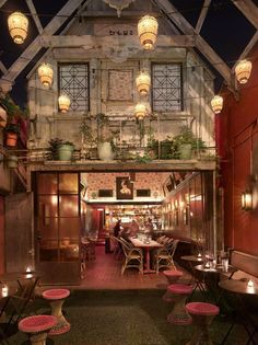 the inside of a restaurant with lots of tables and chairs, lit up by lanterns