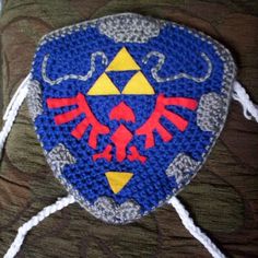 a blue and yellow crocheted hat with an image of the legend of zeldan on it