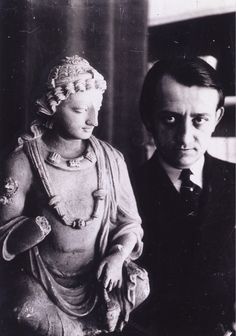 an old black and white photo of a man and woman next to a buddha statue