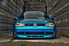 a blue car parked in front of stacks of crates