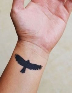 a hand with a black bird tattoo on it's left arm and the wrist