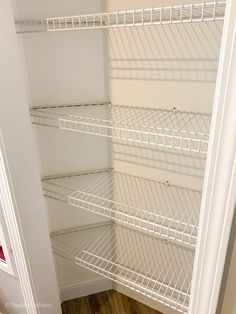 an empty closet with white shelves and wood flooring