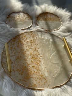 a white and gold plate with two golden spoons sitting on it's side