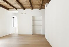 an empty white room with wooden floors and exposed beams on the ceiling is seen in this image