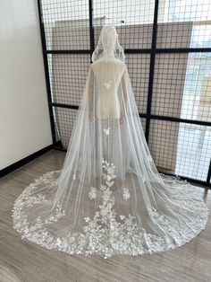 a bridal gown on display in front of a window with sheer veil and flowers