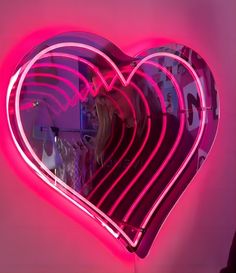 a heart shaped neon sign hanging from the side of a wall next to a mirror