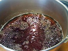 a metal pot filled with liquid on top of a wooden table next to a stove