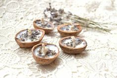 four coconut shells with dried lavenders in them on a lace tablecloth next to flowers