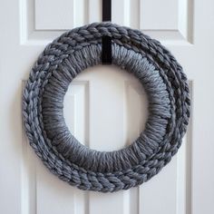 a gray rope wreath hanging on a white door