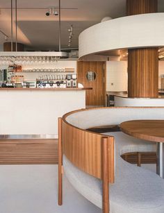 the interior of a modern restaurant with wood and white decor, including circular tables and chairs