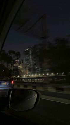 a car driving down the road at night with city lights in the backgroud