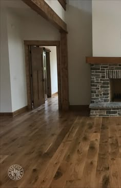 an empty living room with wood floors and a stone fireplace