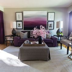 a living room with purple couches and pictures on the wall above them, along with a coffee table