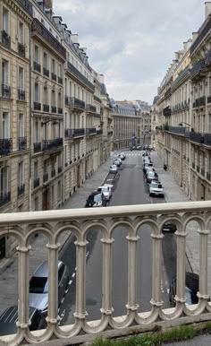 an empty street with cars parked on both sides and tall buildings in the back ground