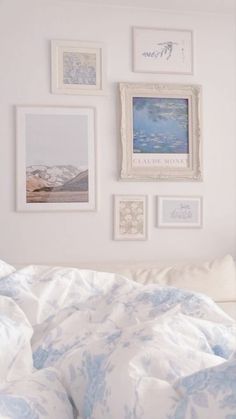 a bed with white sheets and pictures on the wall above it, in front of a window