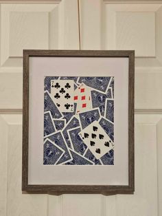 an art piece hanging on the wall with playing cards and dices in blue ink