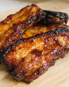 two pieces of meat sitting on top of a wooden cutting board