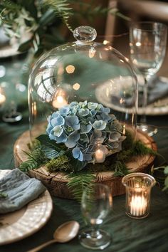 a glass dome with flowers and greenery on it