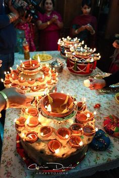 people are gathered around a table with many candles on it and plates in front of them