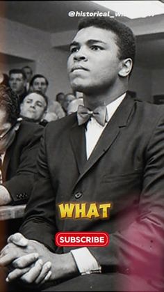 a man in a suit and bow tie sitting at a table with other people behind him