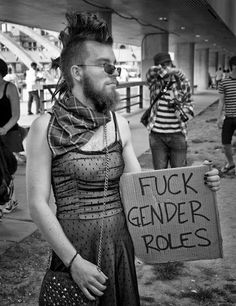 a man holding a sign that says fock gender roles