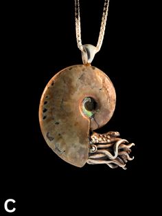 a pendant with an animal's head and shell in the shape of a snail