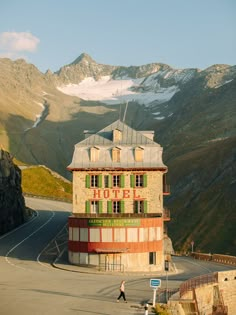 a tall building sitting on the side of a road in front of snow covered mountains