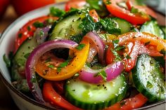 a white bowl filled with cucumbers, tomatoes and onions on top of a wooden table