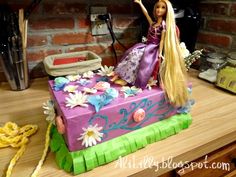 a barbie doll sitting on top of a purple cake with daisies and flowers around it