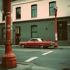 an old red car is parked on the street