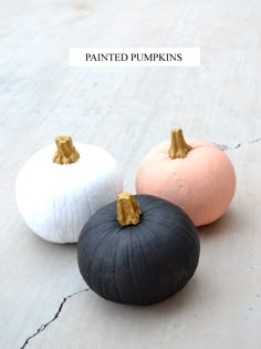 three black and white pumpkins sitting on the ground