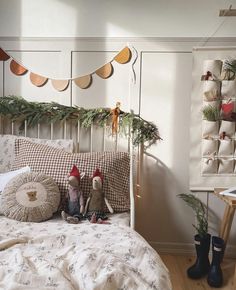 two stuffed animals sitting on top of a bed next to pillows and christmas garlands