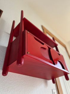 a red shelf that has some sort of object hanging on it's side wall