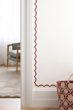 a purse sitting on the floor in front of a white wall with a red scalloped border