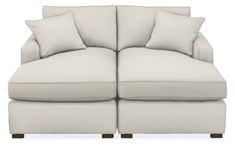 a white couch with two pillows on it's back and one arm facing the camera