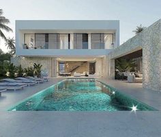 a house with a swimming pool in front of it and lounge chairs around the pool