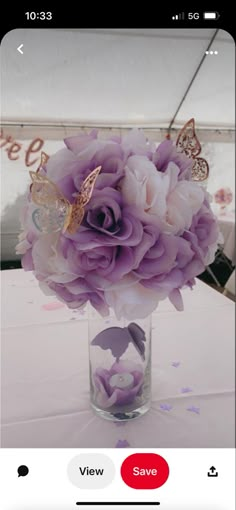 a glass vase filled with purple flowers on top of a white table covered in confetti