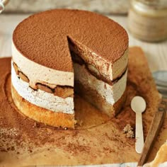 a cake that has been cut in half on a cutting board with a knife and fork next to it