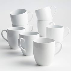 several white coffee cups stacked on top of each other in front of a white background