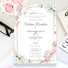 a wedding card with flowers on it next to eyeglasses