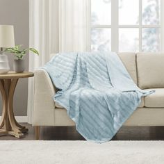 a living room with a white couch and blue blanket