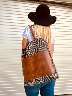 a woman wearing a black cowboy hat and carrying a brown leather bag on her back