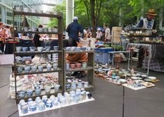 an outdoor flea market with people looking at various items on tables and in front of them