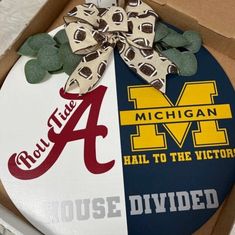 a cake in the shape of a football with a bow on top and michigan logo