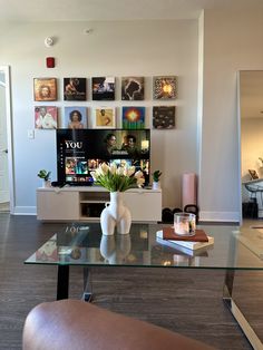 a living room with a glass table and pictures on the wall